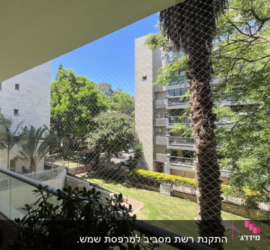 אדם עומד במרפסת עם רשת נגד יונים